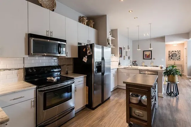 a kitchen with stainless steel appliances a dining table chairs refrigerator and sink