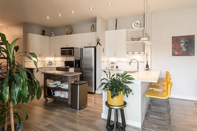 a kitchen with stainless steel appliances kitchen island granite countertop a refrigerator a sink a stove and white cabinets