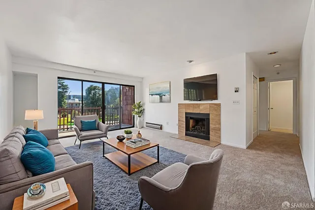 a living room with furniture a fireplace and a floor to ceiling window