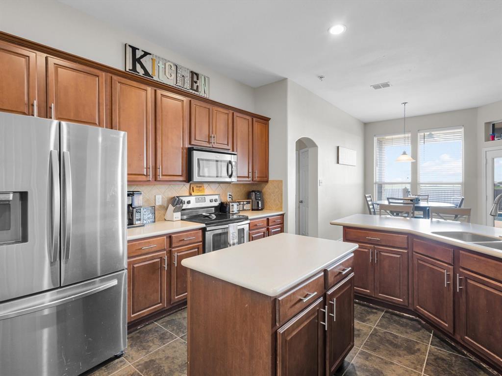 205 King George Road Ponder, TX 76259 - Photo 4 of 37 Kitchen featuring a stainless steel French door refrigerator, wood cabinetry, tile flooring, and an island with a light-colored countertop
