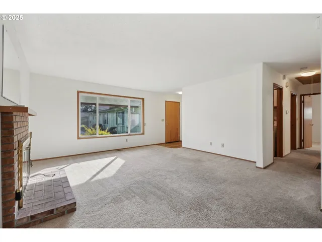a view of an empty room with a fireplace and a window