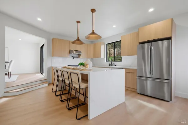 a kitchen with stainless steel appliances a dining table chairs stove and refrigerator