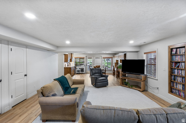 882 Sego Lily Way Mapleton, UT 84664 - Photo 23 of 41 Open-concept living space featuring wood-finish flooring, recessed lighting, white walls, and a built-in wood bookshelf