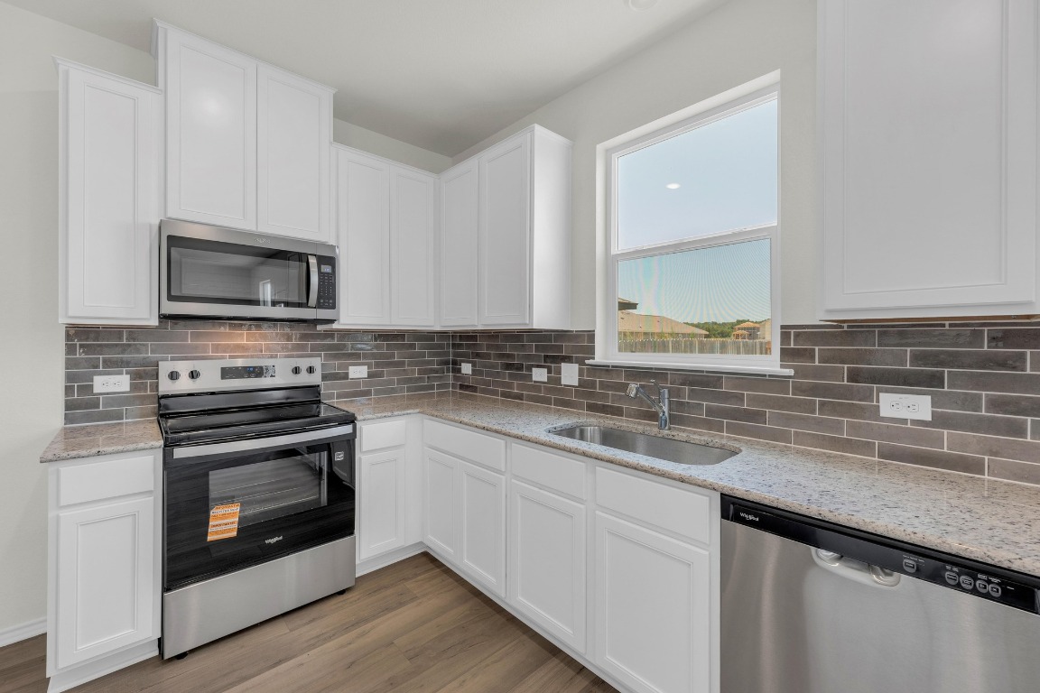 200 Lucky Texan Road Jarrell, TX 76537 - Photo 12 of 34 a kitchen with granite countertop a stove a sink and a microwave