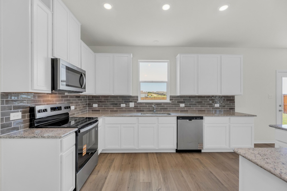 200 Lucky Texan Road Jarrell, TX 76537 - Photo 13 of 34 a kitchen with stainless steel appliances granite countertop a stove a sink and a microwave