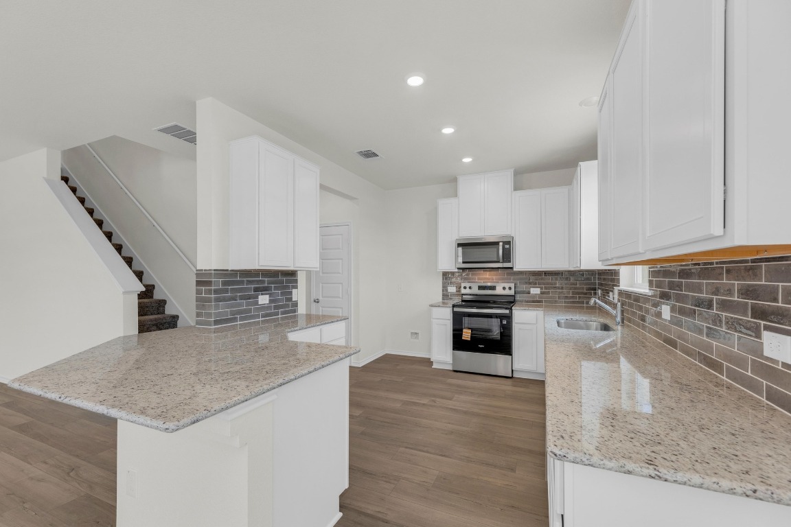 200 Lucky Texan Road Jarrell, TX 76537 - Photo 7 of 34 a kitchen with stainless steel appliances kitchen island granite countertop a stove and a sink