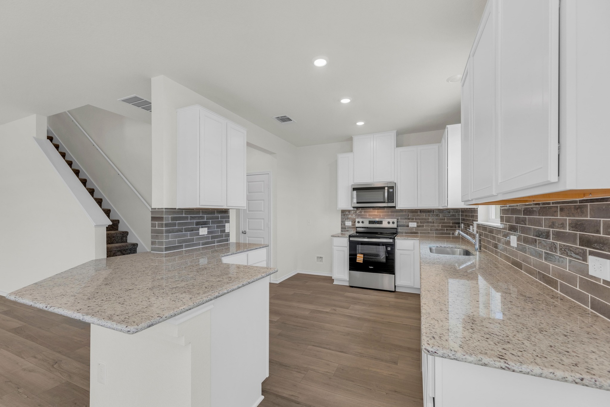 200 Lucky Texan Road Jarrell, TX 76537 - Photo 7 of 34 a kitchen with stainless steel appliances kitchen island granite countertop a stove and a sink