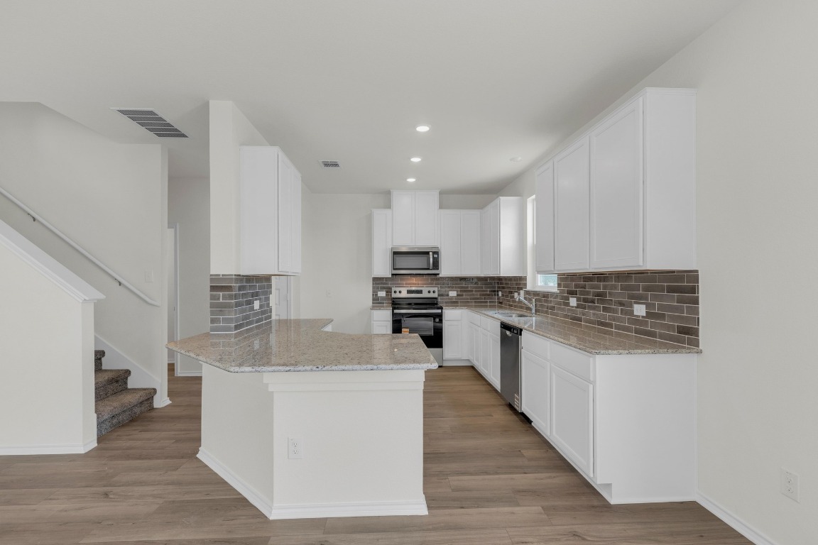 200 Lucky Texan Road Jarrell, TX 76537 - Photo 8 of 34 a kitchen with stainless steel appliances granite countertop a sink a stove top oven a counter space and cabinets