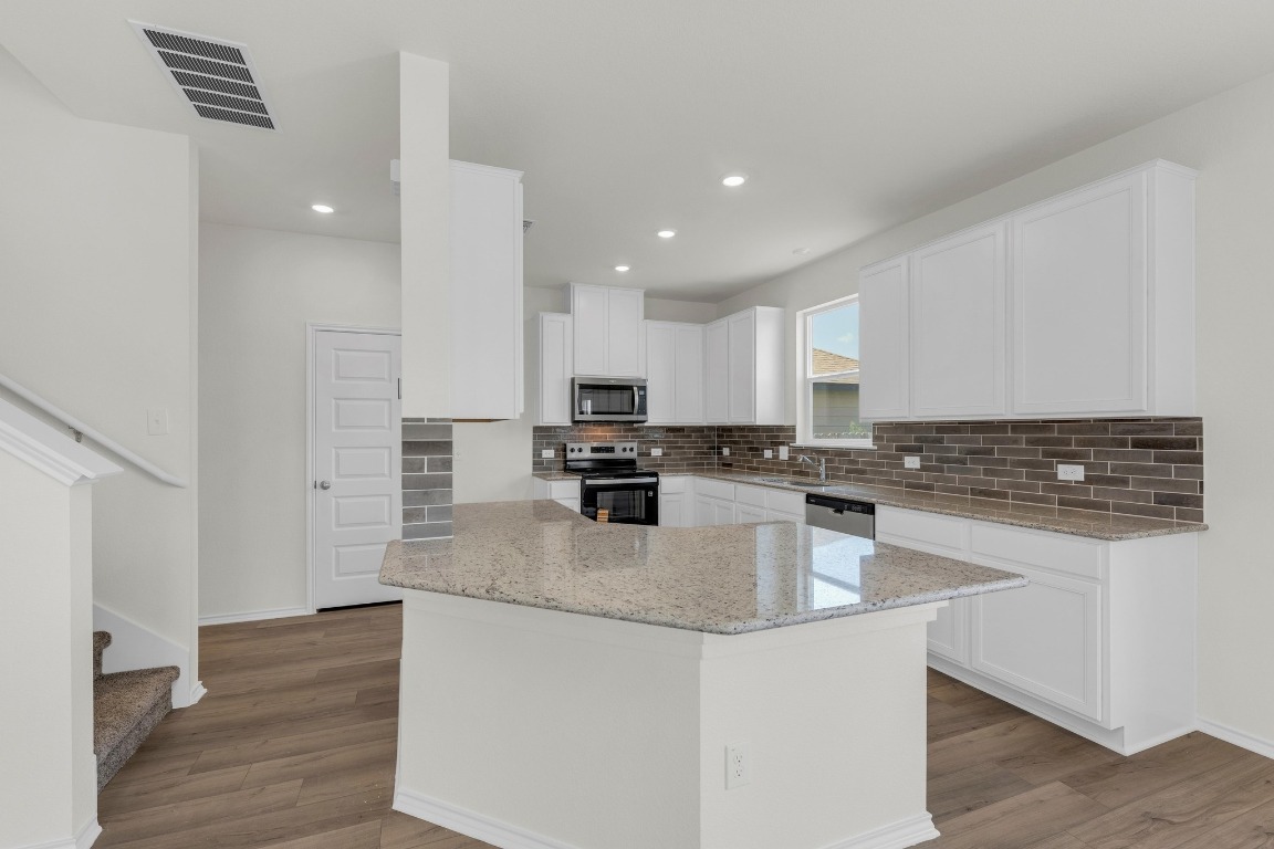 200 Lucky Texan Road Jarrell, TX 76537 - Photo 9 of 34 a kitchen with stainless steel appliances granite countertop a sink dishwasher a refrigerator and white cabinets with wooden floor