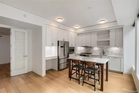 a kitchen with a refrigerator a stove a sink and a dining table with wooden floor