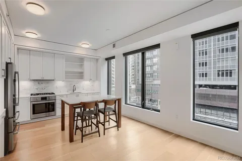 a kitchen with stainless steel appliances granite countertop a stove a sink a refrigerator with white cabinets and wooden floor