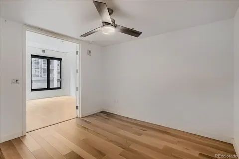 an empty room with wooden floor fan and window