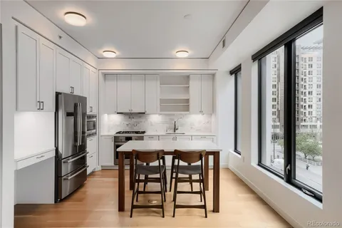 a kitchen with stainless steel appliances a refrigerator a stove a sink dishwasher with a dining table and chairs