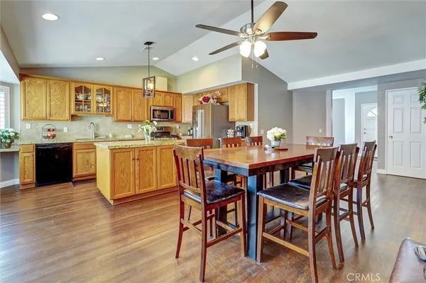 a view of a dining room and livingroom with furniture wooden floor a rug a painting and a chandelier