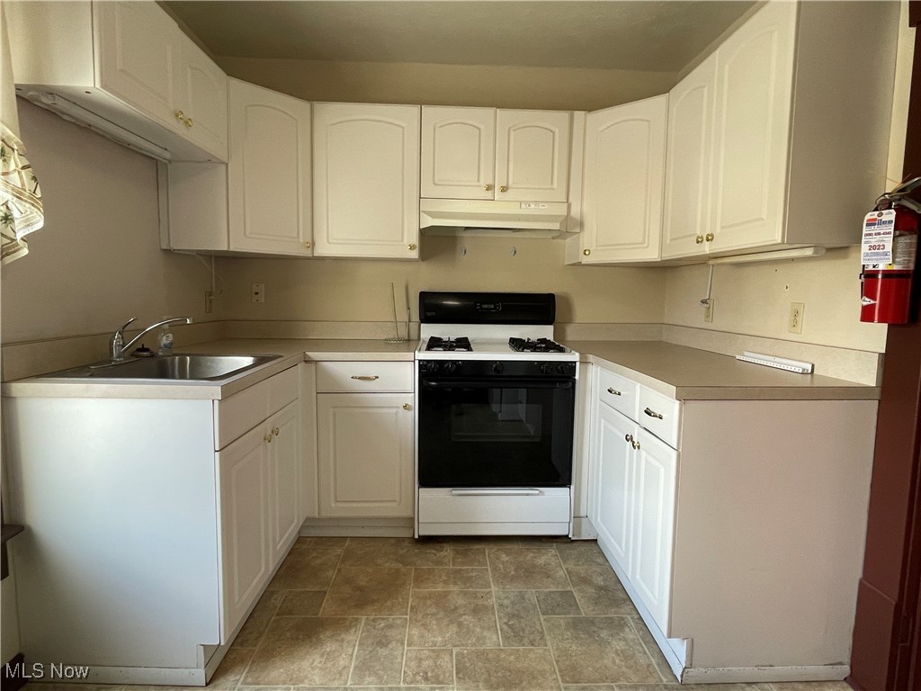 1881 Manchester Road Akron, OH 44314 - Photo 24 of 31 Kitchen with white range with gas stovetop, stone finish flooring, and white cabinets