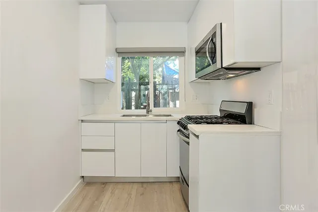 a kitchen with stainless steel appliances granite countertop a stove and a white refrigerator with wooden floor