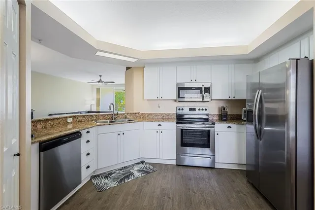 a kitchen with granite countertop white cabinets and stainless steel appliances