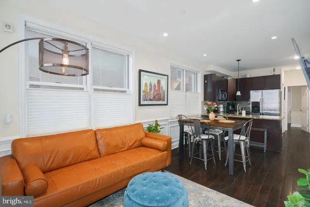 a living room with furniture wooden floor and kitchen view