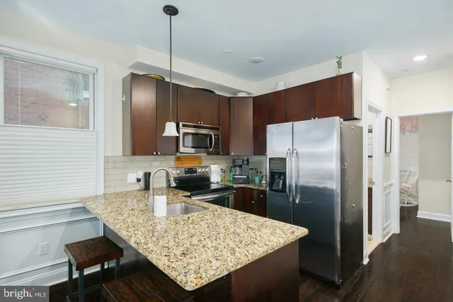 a kitchen with stainless steel appliances granite countertop a refrigerator a stove and a sink