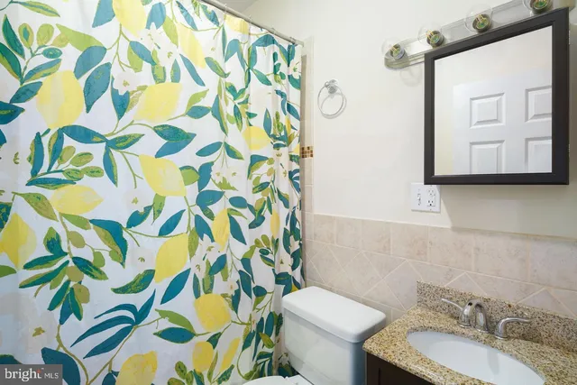 a bathroom with a granite countertop sink and a toilet