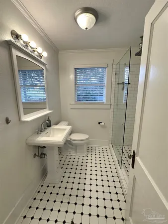 a bathroom with a sink a toilet a mirror and shower