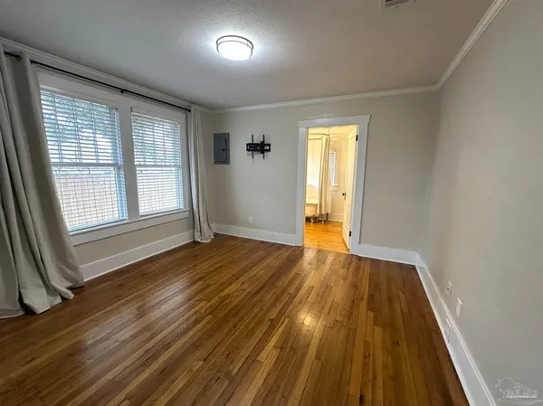 an empty room with wooden floor and windows