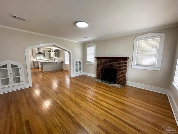 an empty room with windows fireplace and wooden floor
