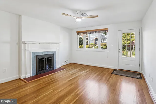 an empty room with windows fireplace and wooden floor