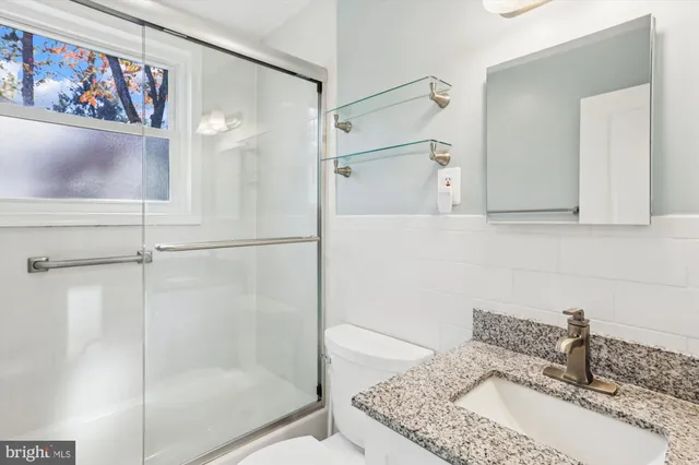 a bathroom with a granite countertop sink mirror and shower