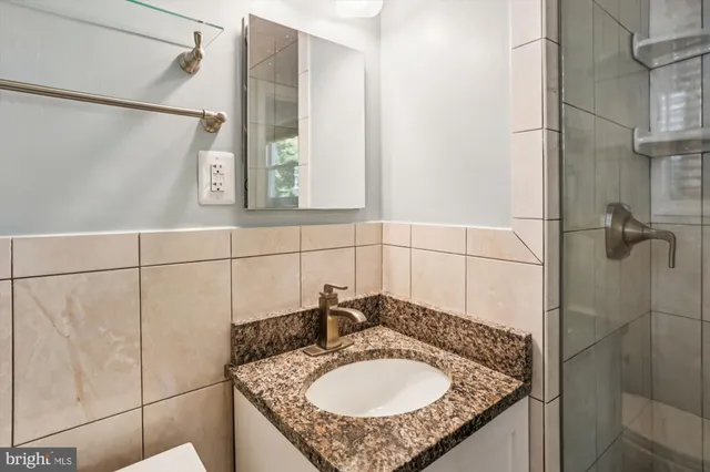 a bathroom with a granite countertop shower sink and mirror