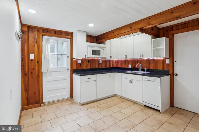 a kitchen with white cabinets and sink