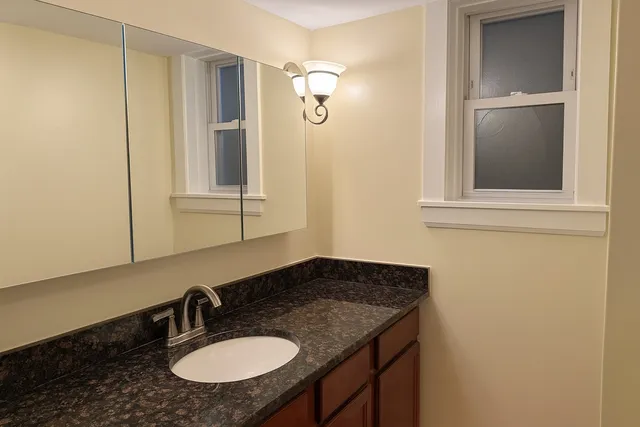 a bathroom with a granite countertop sink and a mirror