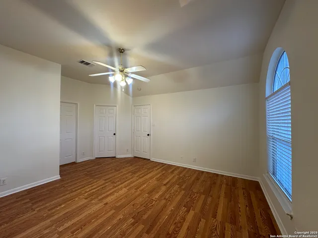 a view of empty room with wooden floor and fan