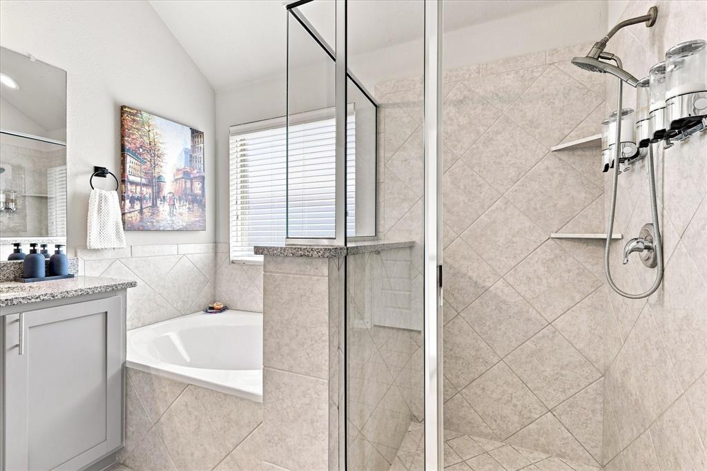 15729 Preble Road Fort Worth, TX 76177 - Photo 22 of 37 Spacious Primary Bath features a Vaulted Ceiling, Dual-sink Granite Mirrored Vanity, Abundant Cabinetry, Tile Flooring. A Deep Soaking Tub with Tiled Surround Complemented by a Separate Tiled Walk-in Shower with Frameless Glass Enclosure and Built-in Corner Shelves. There's also Convenient Access to the Linen and Walk-in Closets.