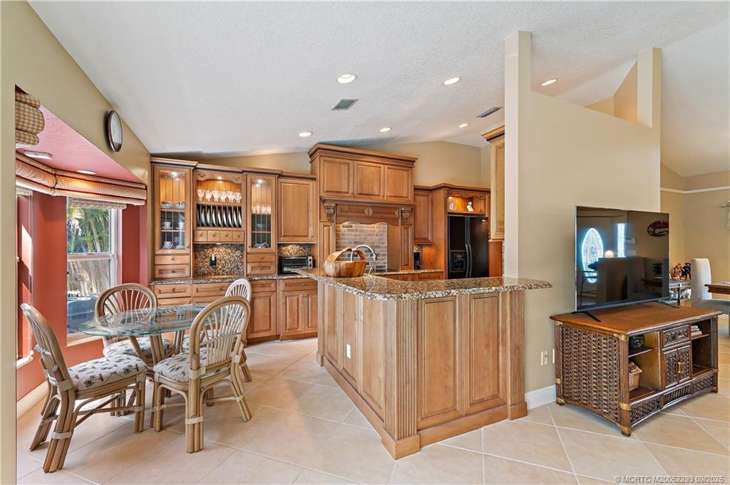 815 Southwest Rustic Circle Stuart, FL 34997 - Photo 7 of 20 a kitchen with stainless steel appliances kitchen island granite countertop a table and chairs