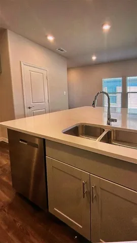 a view of a kitchen with kitchen island a sink wooden floor and black appliances