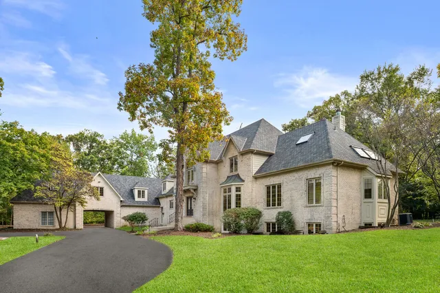 a front view of a house with a garden and trees