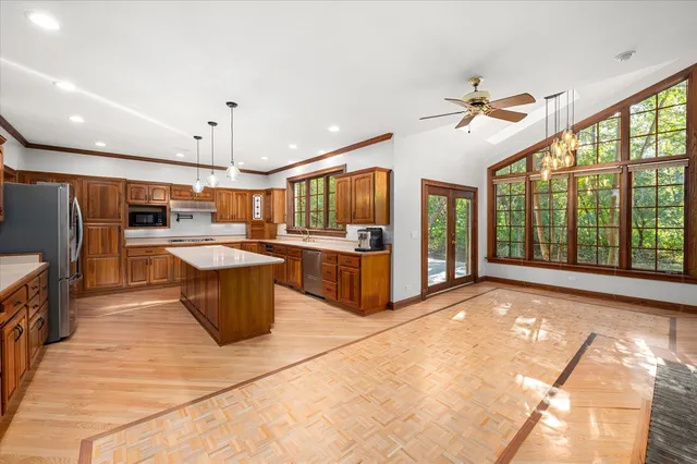 a large kitchen with kitchen island a large counter top space a sink stainless steel appliances and cabinets