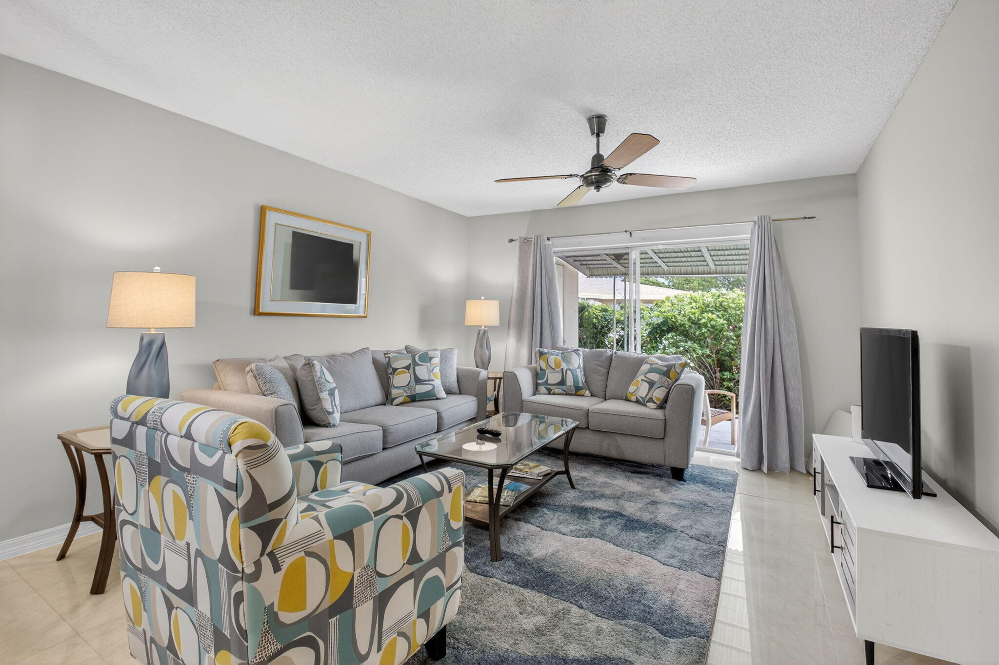 8633 Chevy Chase Drive Boca Raton, FL 33433 - Photo 3 of 43 a living room with furniture a large window and a flat screen tv
