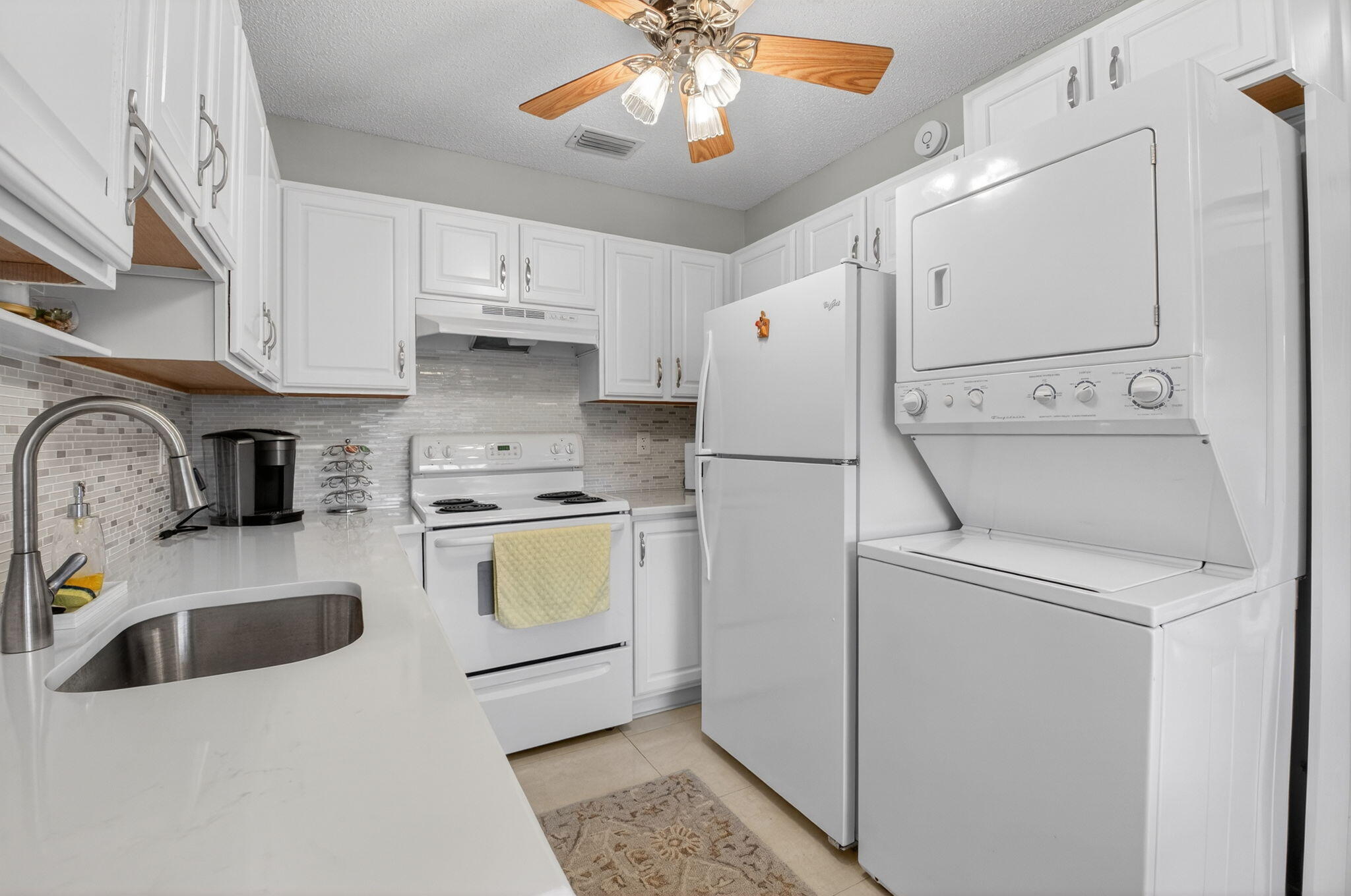 8633 Chevy Chase Drive Boca Raton, FL 33433 - Photo 10 of 43 a kitchen with a white cabinets and white appliances