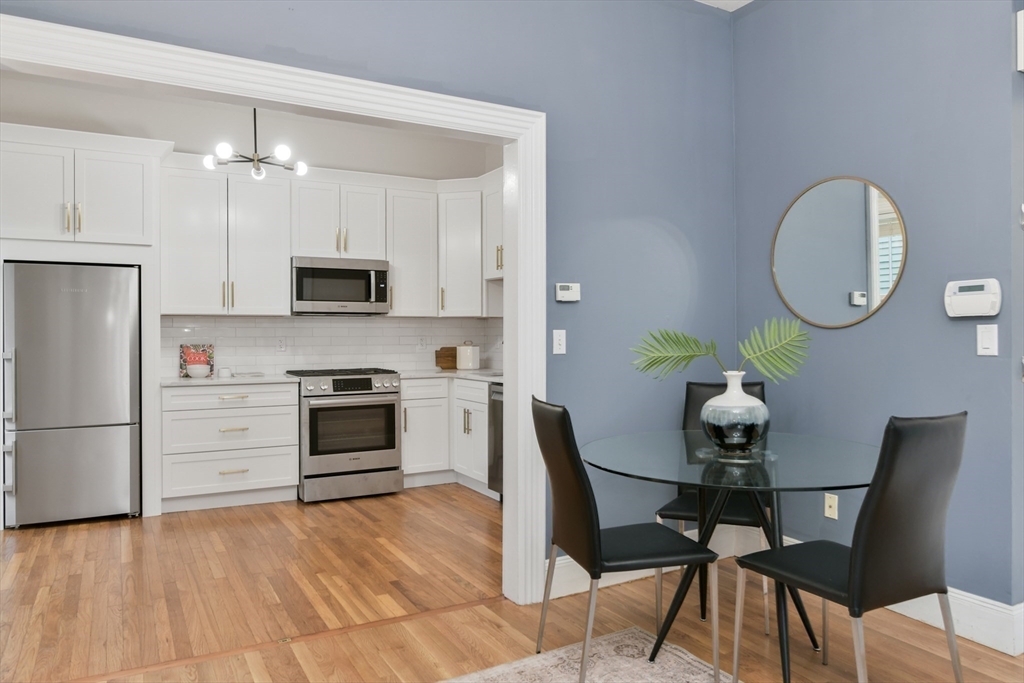 111 Inman Street, Unit A Cambridge, MA 02139 - Photo 6 of 18 a kitchen with stainless steel appliances a stove a table chairs and a refrigerator