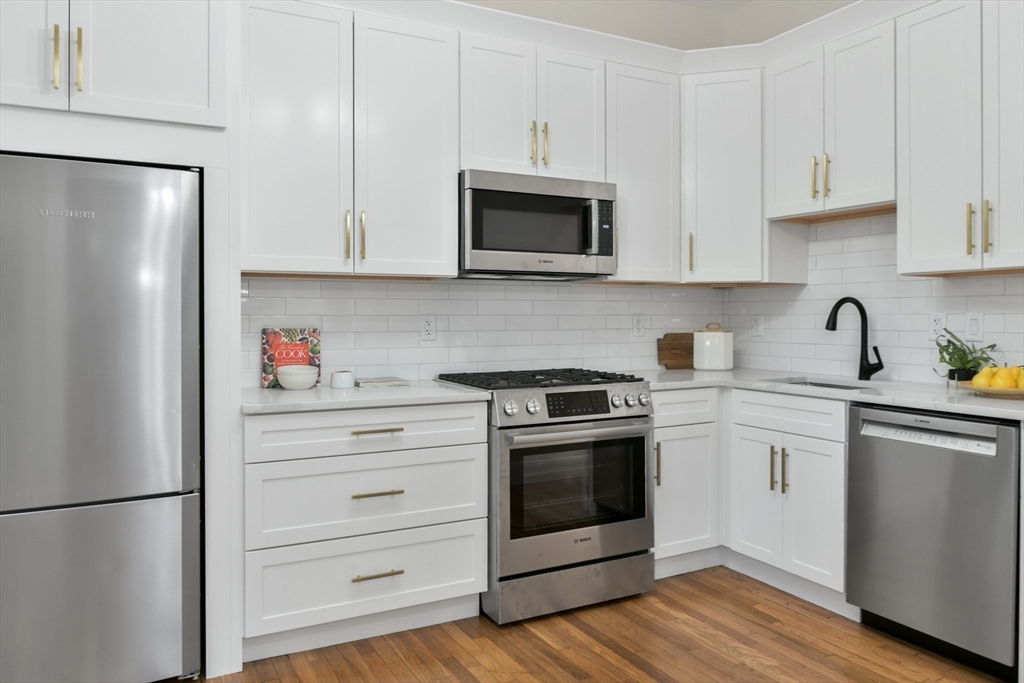 111 Inman Street, Unit A Cambridge, MA 02139 - Photo 8 of 18 a kitchen with stainless steel appliances white cabinets and a refrigerator