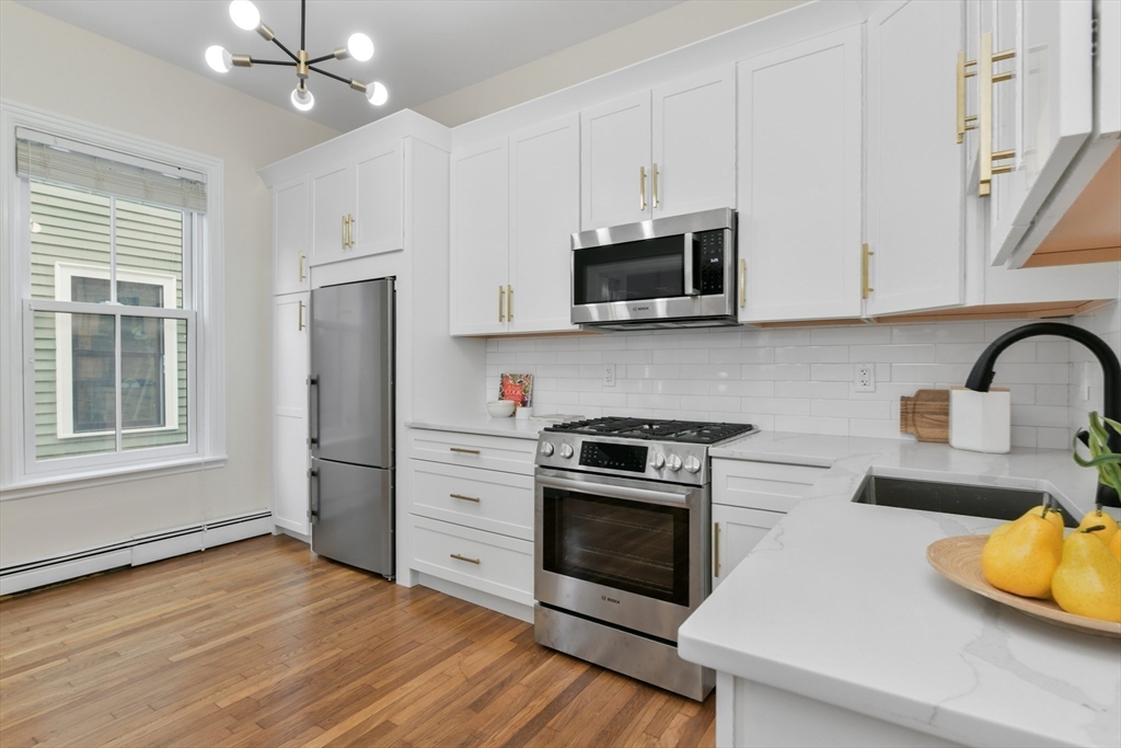 111 Inman Street, Unit A Cambridge, MA 02139 - Photo 10 of 18 a kitchen with stainless steel appliances a stove microwave and sink