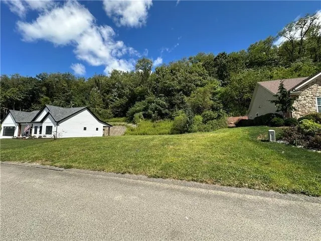 a view of a big house with a big yard and large trees