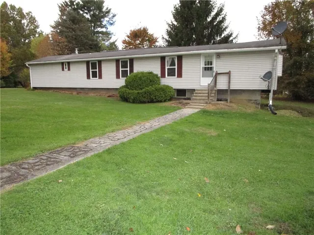 a view of a yard in front of a house with large windows