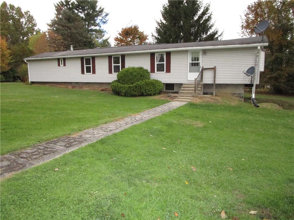 a view of a yard in front of a house with large windows