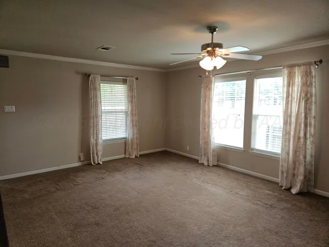 an empty room with windows and fan