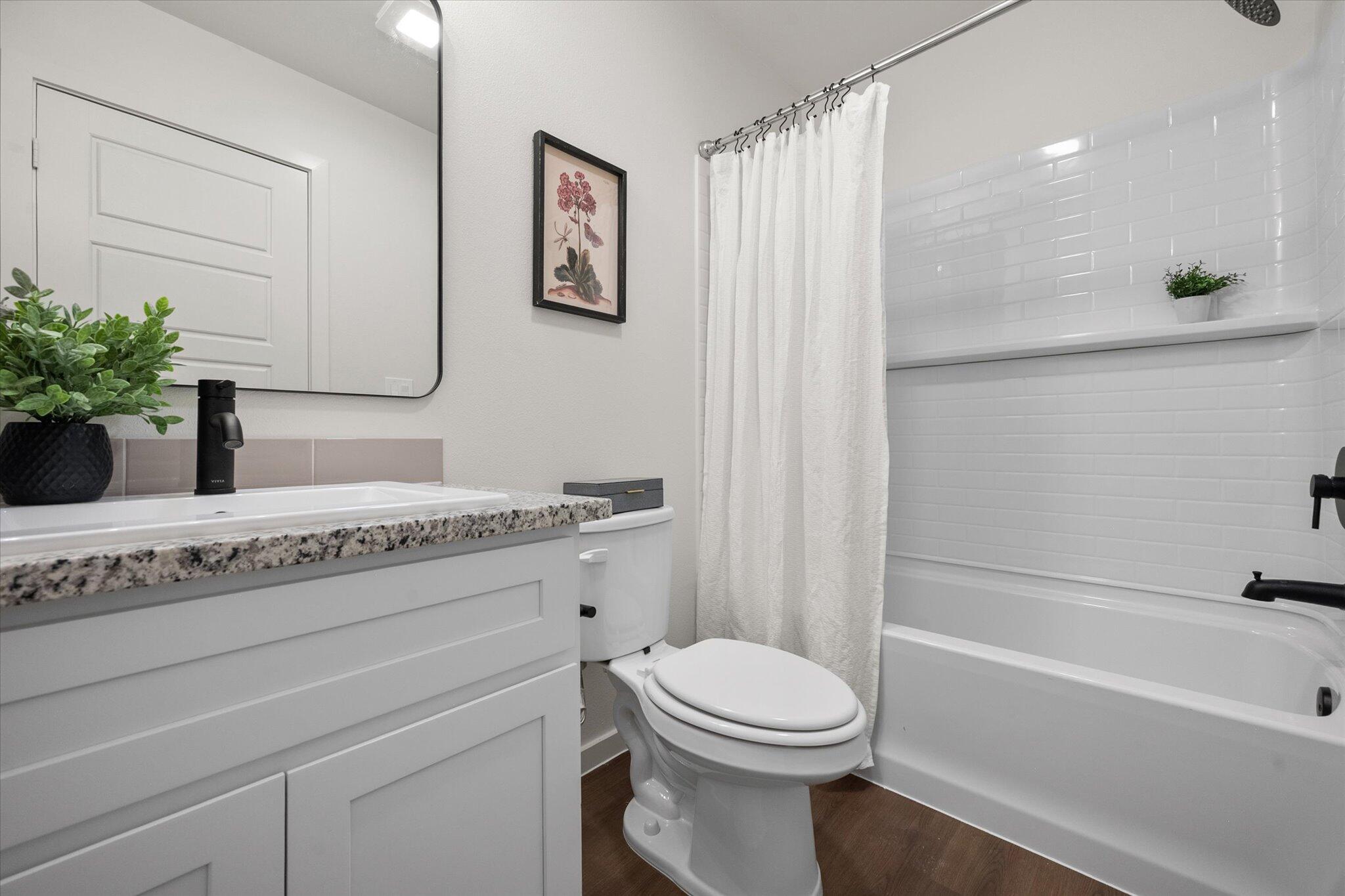 5505 Smith Street Lubbock, TX 79416 - Photo 17 of 18 a bathroom with a granite countertop bathtub sink vanity mirror and toilet