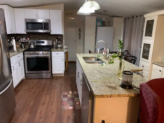 a kitchen with stainless steel appliances granite countertop a sink a stove and cabinets
