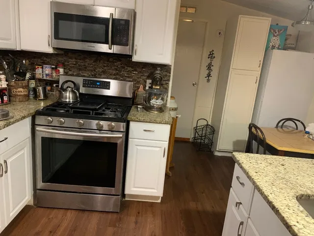 a kitchen with stainless steel appliances granite countertop a stove a sink and a refrigerator